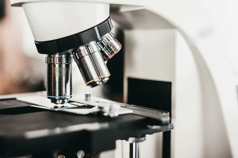 Primer plano de un microscopio de laboratorio con sus objetivos sobre la platina.