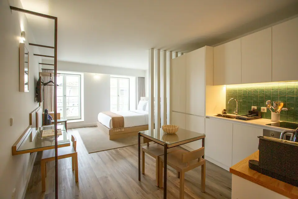Monoambiente amoblado con cocina integrada, comedor pequeño y dormitorio al fondo.