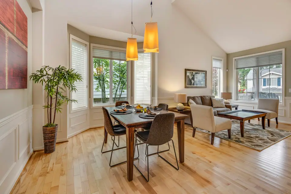 Comedor con mesa de madera, lámparas colgantes y living integrado.