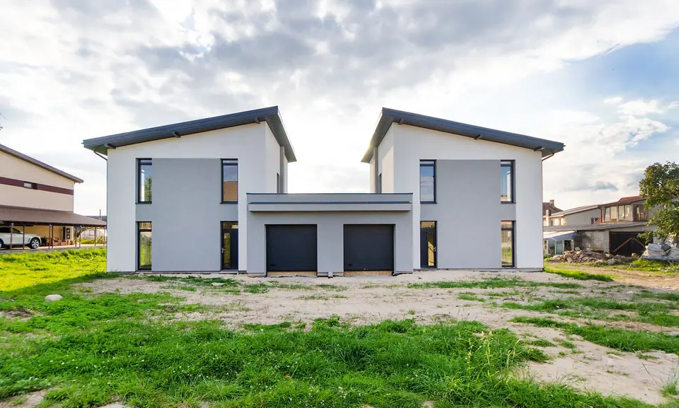 Dúplex moderno de dos casas gemelas con garajes y terreno con césped.