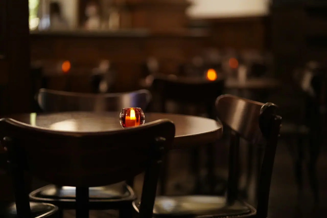 Mesa redonda de madera con una vela encendida en un salón cálido y en penumbra