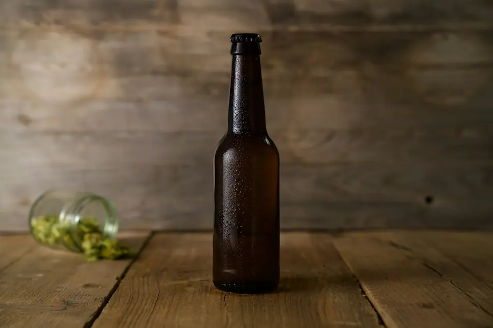 Botella de cerveza fría, sin etiqueta, sobre una mesa de madera