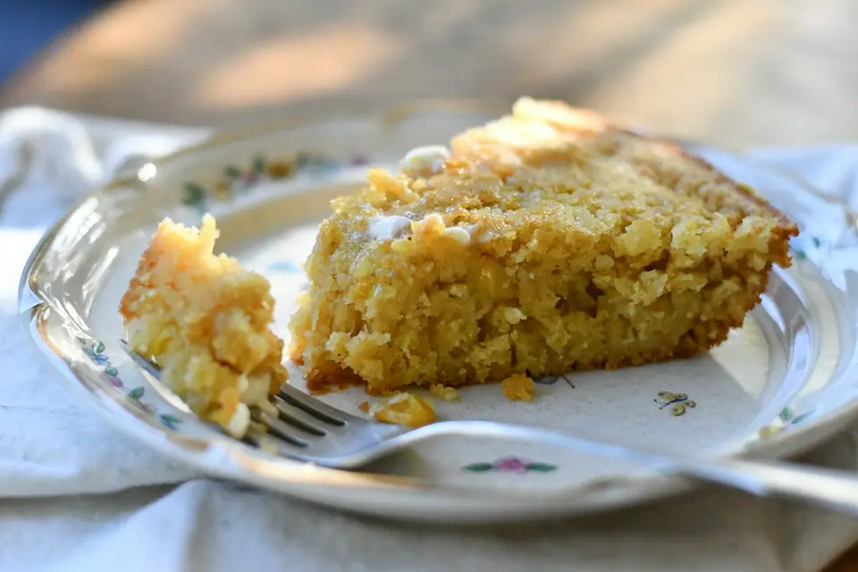 Porción de chipa guasu dorada, con granos de choclo, en un plato con tenedor