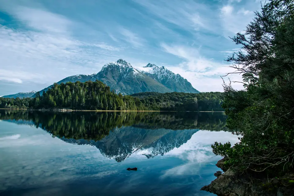 Lago patagónico que refleja un cerro nevado y el bosque cerca de Bariloche.