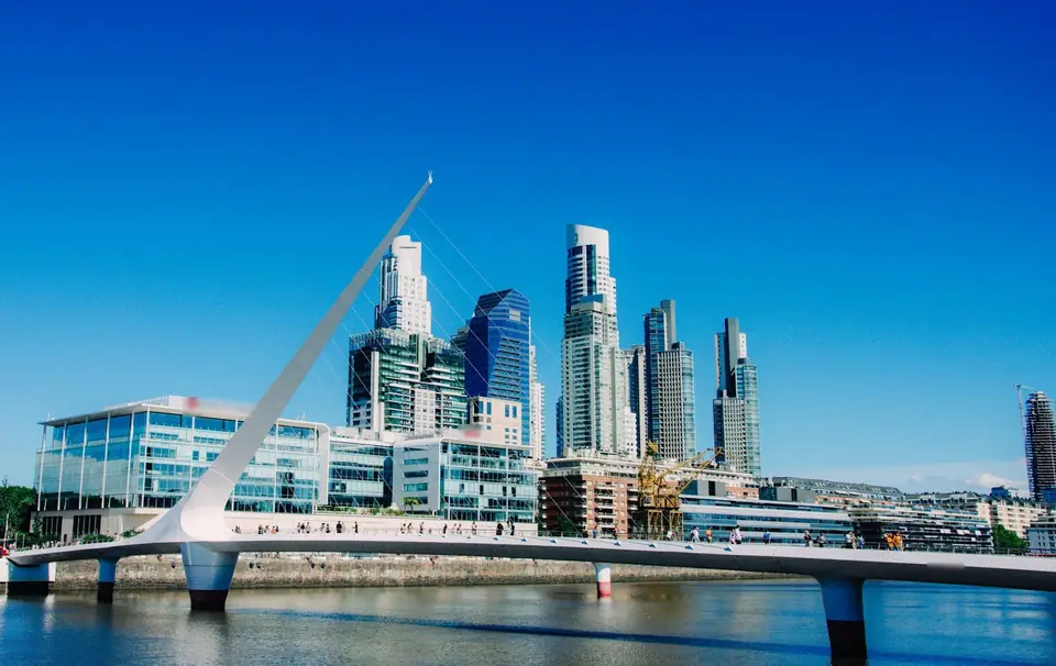 Puente de la Mujer y las torres de Puerto Madero en Buenos Aires bajo un cielo azul.