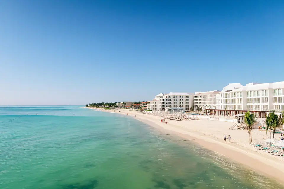 Playa de arena blanca y mar turquesa con hoteles en la costa caribeña.