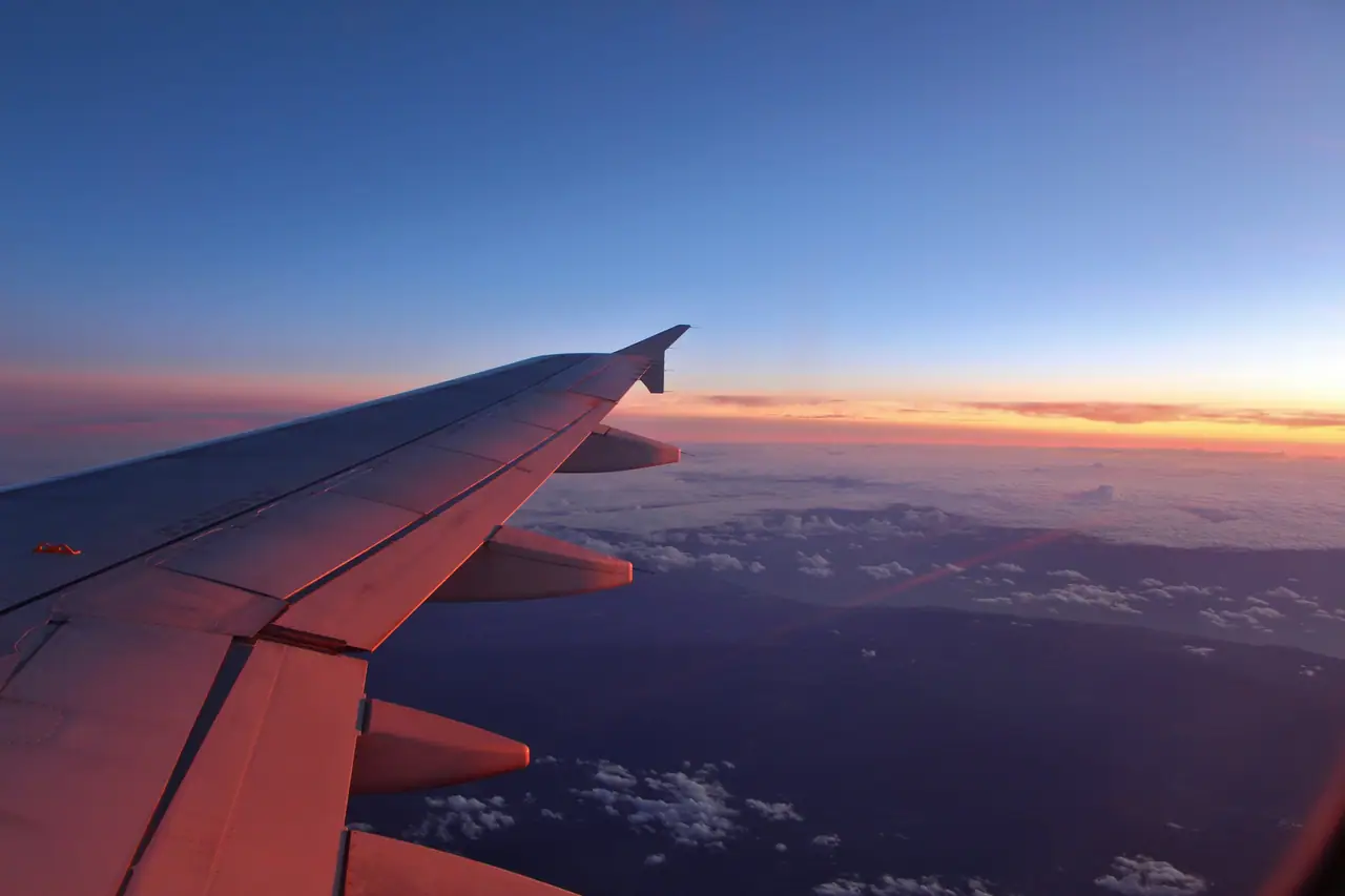 Ala de avión sobre las nubes al atardecer vista desde la ventanilla.